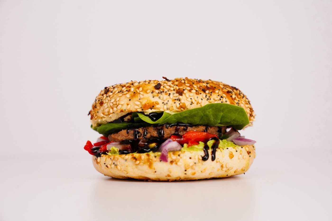 Burger on an everything bagel with greens, roasted red pepper and balsamic