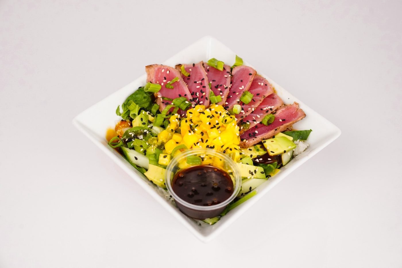 Seared tuna rice bowl with mango, avocado and scallions